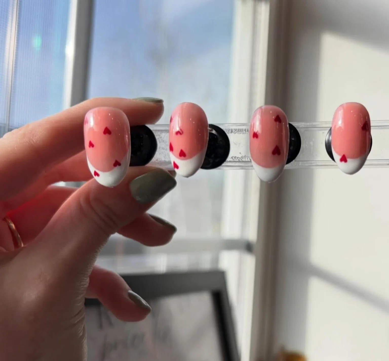 Pink press-on nail set with tiny red hearts and white tips